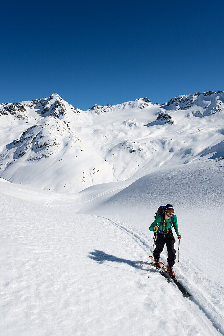 Skitourengeher vor dem Grialetschgebiet mit Grialetschgletscher (Vadret da Grialetsch), Piz Sarsura (rechts, 3178 m) und Piz Sarsura Pitschen links (3134 m), Graubünden, Schweiz, Europa