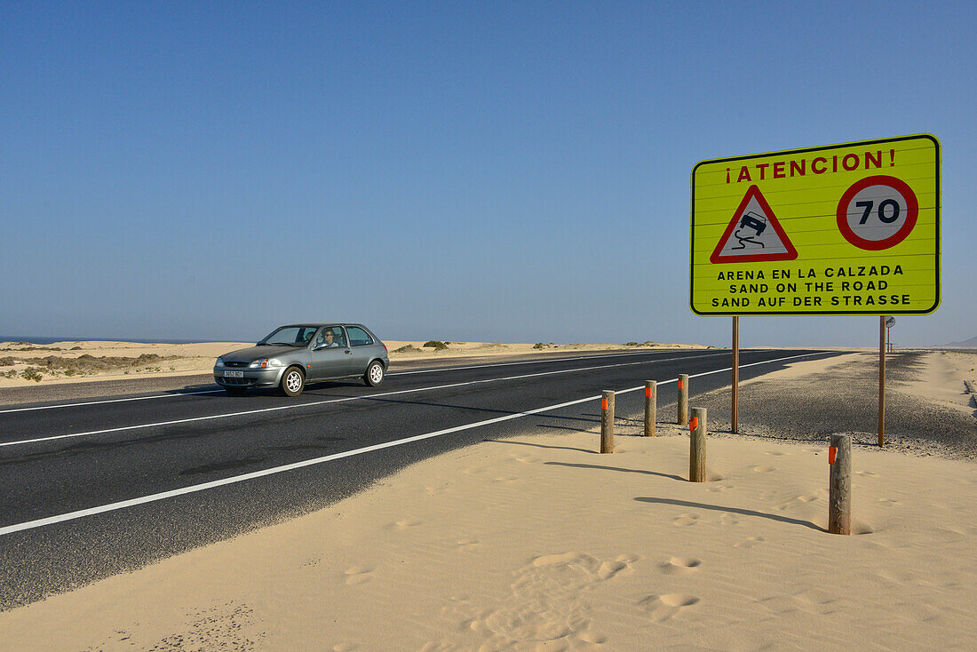 Warnschild vor Sand auf der Küstenstraße, Playa dunas de Corralejo, Corralejo, Fuerteventura, Kanaren, Kanarische Inseln, Spanien