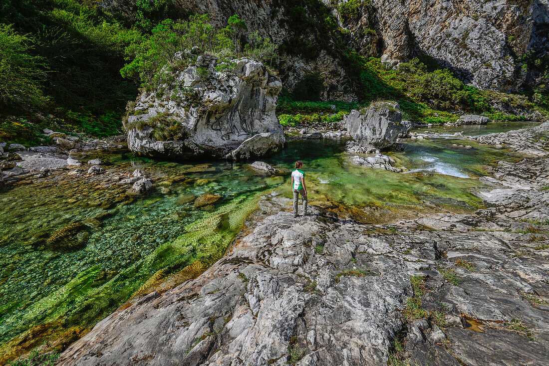 Young woman in a canyon on the shore of Rio Cares, Puente de Poncebos, mountains of Parque Nacional de los Picos de Europa, Asturias, Spain