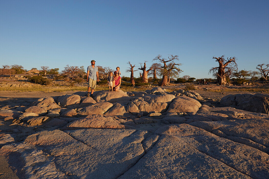 Familie betrachtet Aussicht im Sonnenuntergang, Kubu Island, Makgadikgadi Pans Nationalpark, Botswana