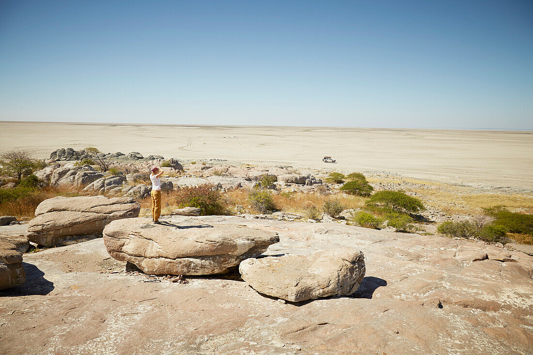 Woman standing on a rock while looking over salt desert, Kubu Island, Makgadikgadi Pans National Park, Botswana
