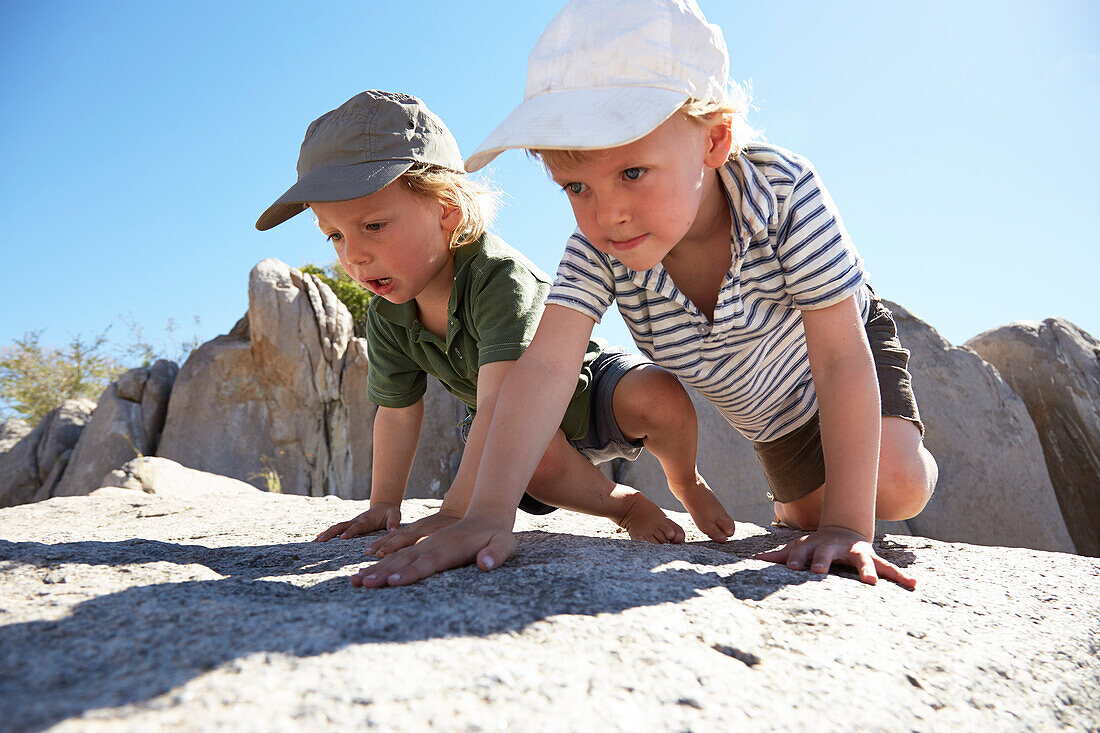 Zwei Jungen krabbeln über Felsen, Kubu Island, Makgadikgadi Pans Nationalpark, Botswana