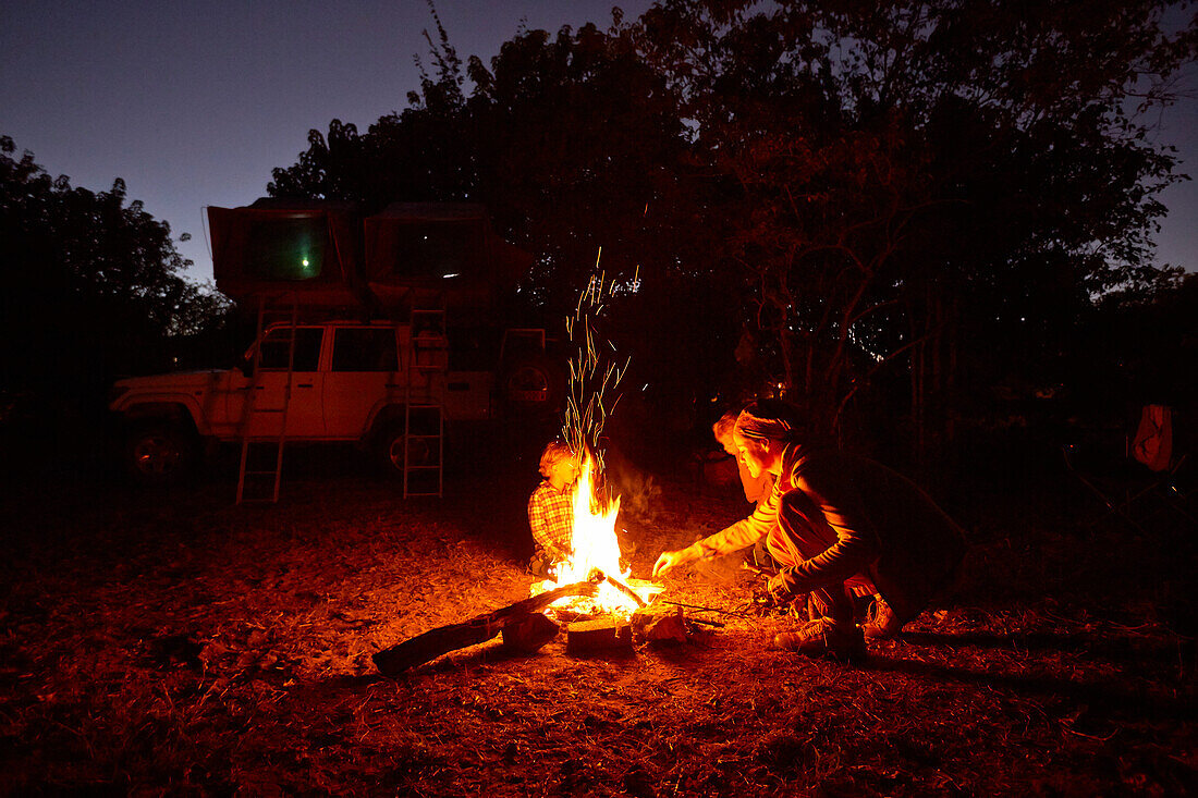 Family sitting around a camp fire, Maun, Okavango Delta, Botswana