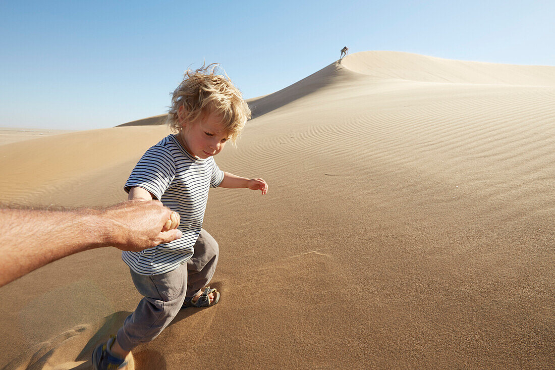Sohn zieht Vater eine Sanddüne hoch, Dune 7, Walvis Bay, Erongo, Namibia