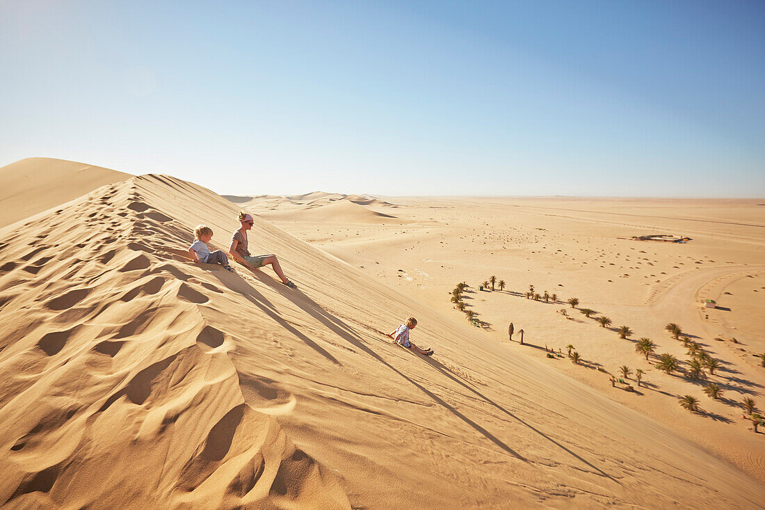 Familie rutscht eine Sanddüne runter, Dune 7, Walvis Bay, Erongo, Namibia