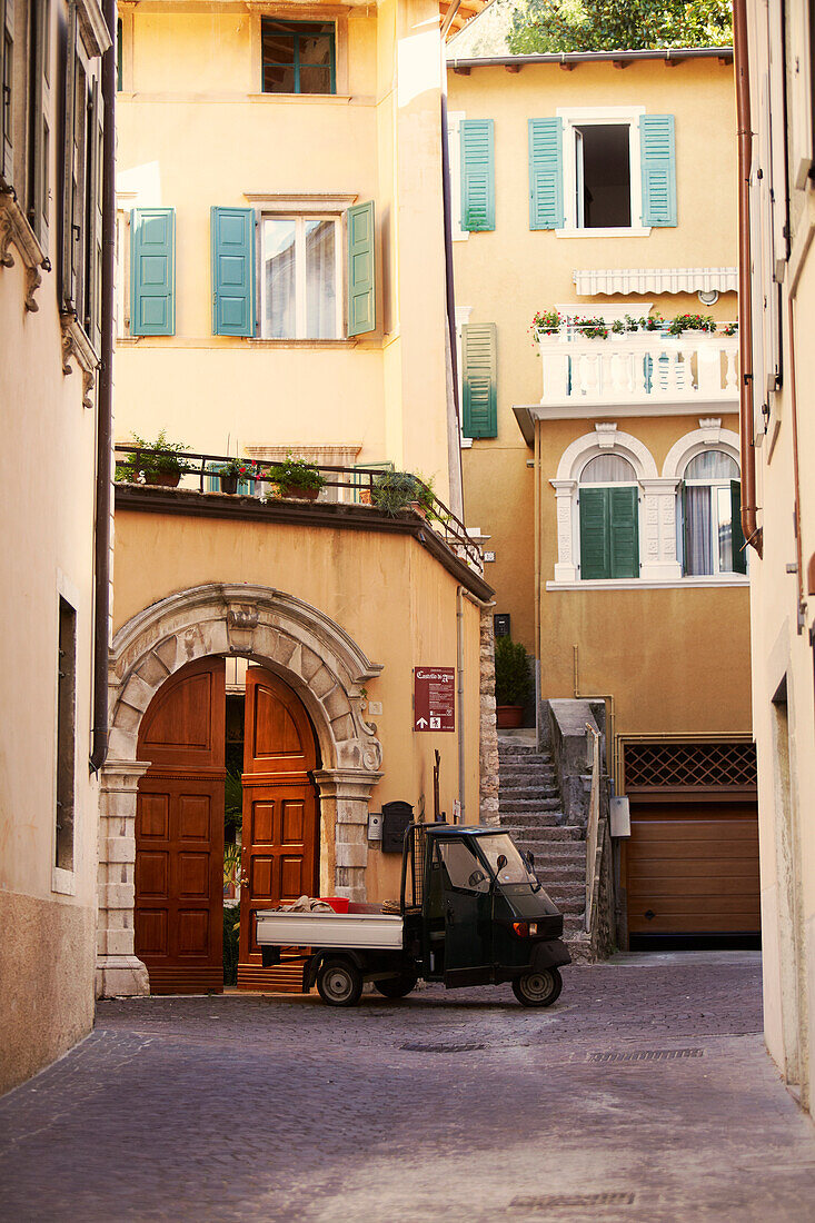 Ape pickup passing the old town, Arco, Trentino, Italy