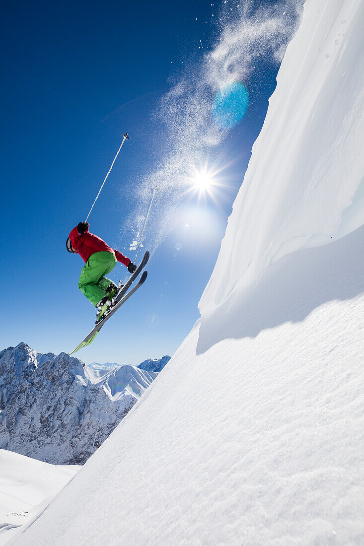 freeride skier jumping over snow cornice, Zugspitze, Hochwanner and Gatterl in the background, Upper Bavaria, Germany