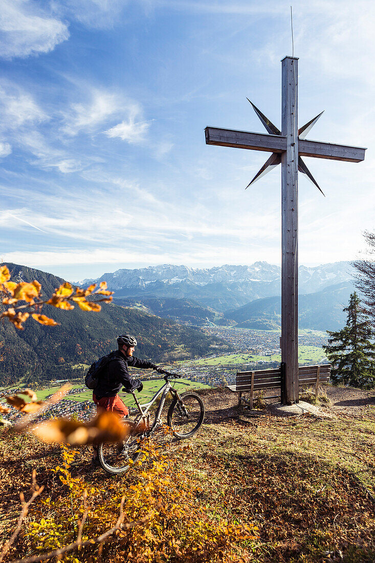 mountain biker and summit cross on Schafskopf, Farchant, Bavaria, Germany
