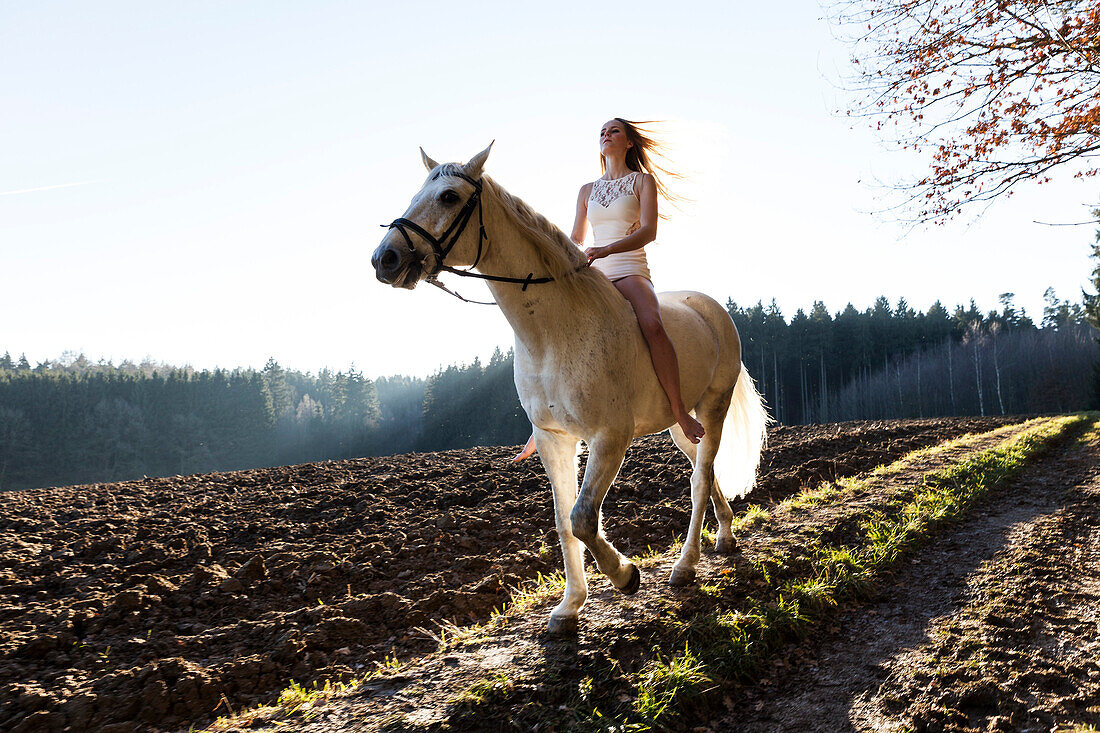 Mädchen reitet in weißem Kleidchen auf Pferd, Freising, Bayern, Deutschland