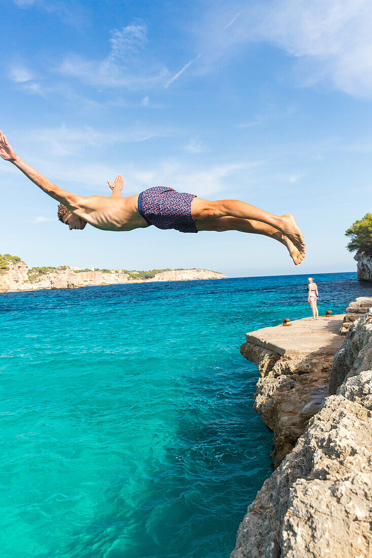 Young man diving into the turquoise blue water, Cala Sa Nau, tourist, Mediterranean Sea, near Portocolom, Majorca, Balearic Islands, Spain, Europe