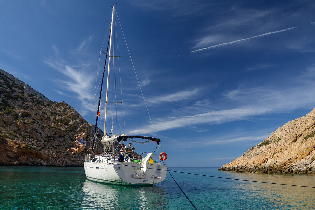 Mann springt Salto von ankernder Segelyacht in einsamer Bucht der griechischen  Insel Syphnos (Sifnos), Ägäis, Kykladen, Griechenland