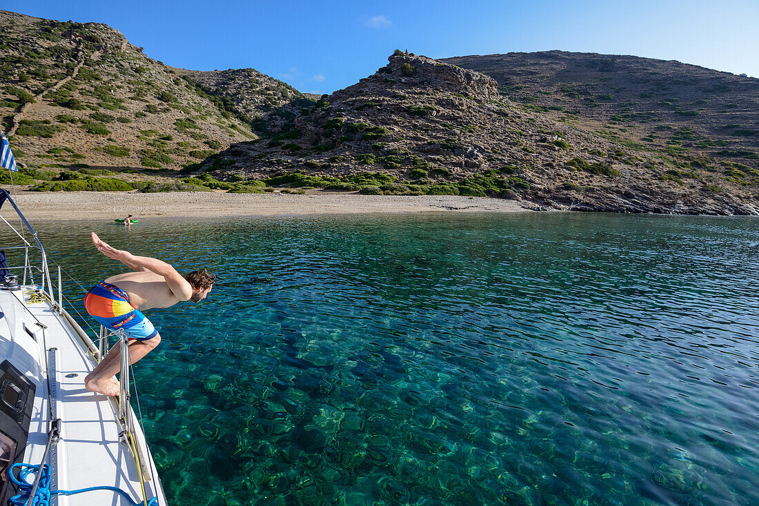 Mann springt von Segelyacht in einesame Bucht der griechischen Insel Kithnos, Ägäis, Kolona, Kykladen, Griechenland