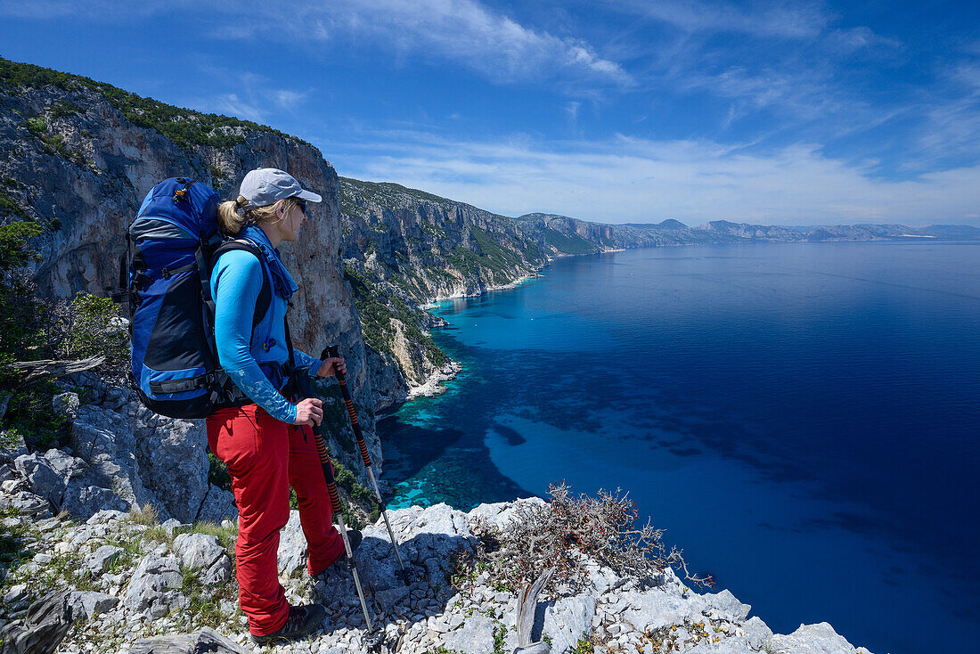 Eine junge Frau mit Trekkingausrüstung steht oberhalb des Meeres, Golfo di Orosei, an der gebirgigen Küste, Selvaggio Blu, Sardinien, Italien, Europa