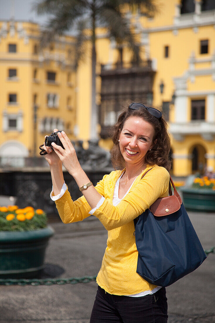 Cheerful woman with camera on Plaza de Armas square, Lima, Lima, Peru