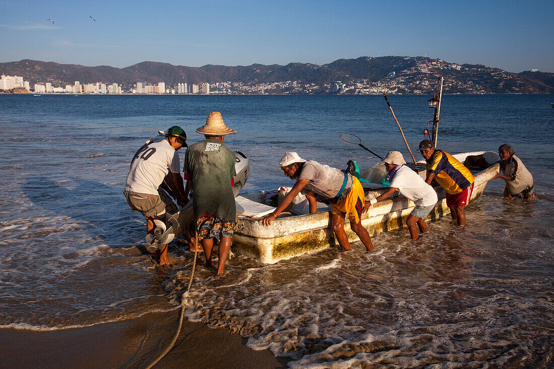 Fischer entladen ihren Fang von einem Fischerboot am Strand Playa Las Hamacas Acapulco, Guerrero, Mexiko, Mittelamerika