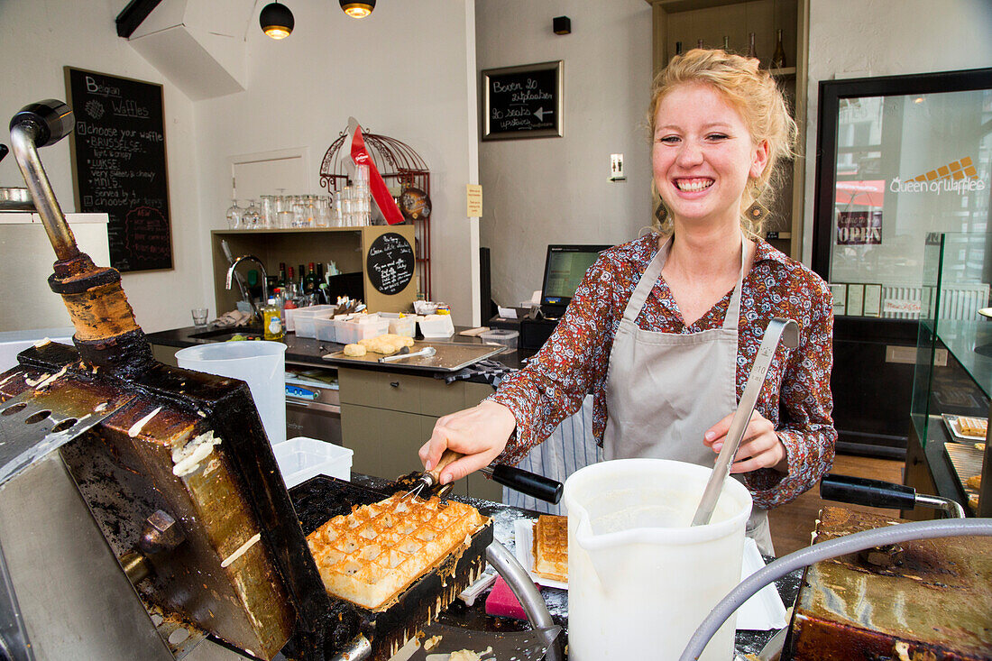 Junge Frau backt frische Gaufre Waffeln in der Queen of Waffles Waffelbäckerei, Antwerpen, Flandern, Belgien, Europa