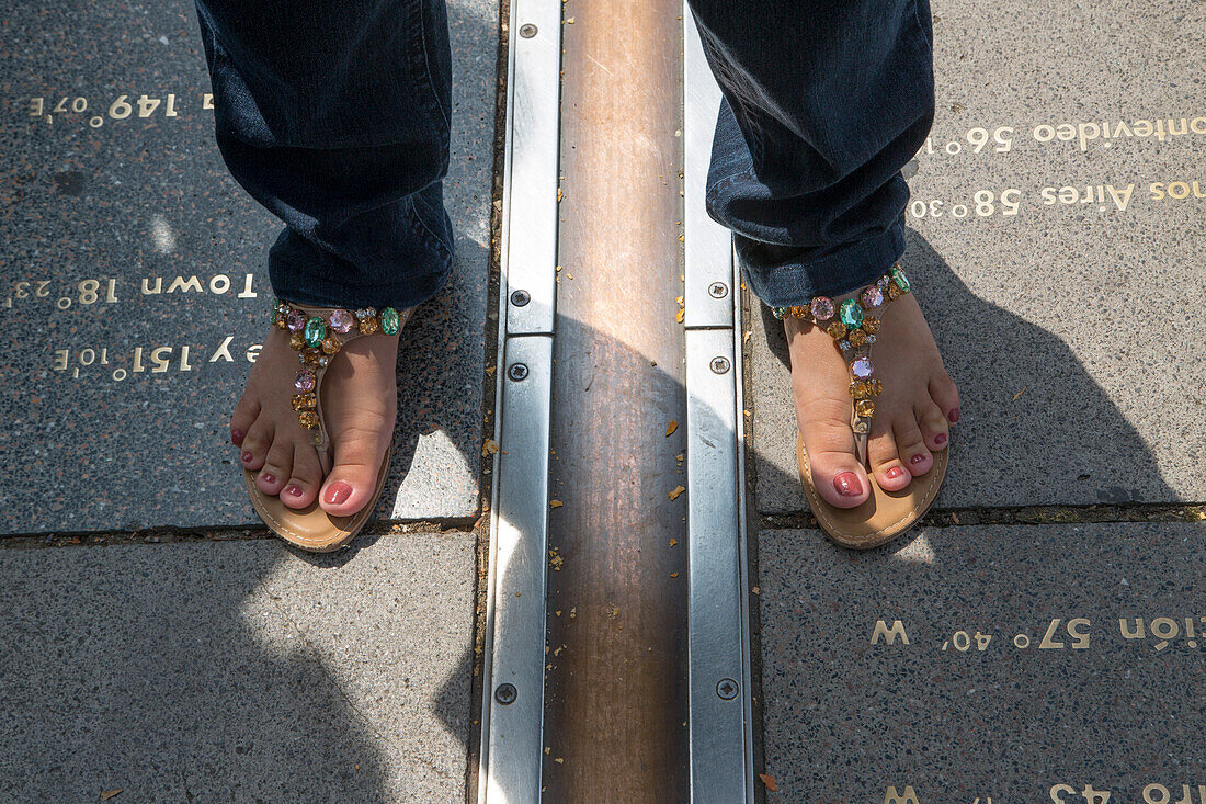 Woman with sandals stands on Prime Meridian line at the Royal Observatory, Greenwich, London, England, United Kingdom
