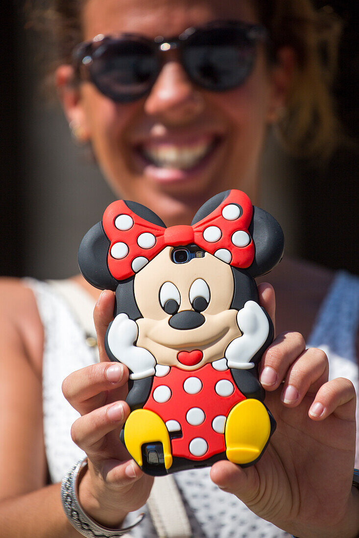 Frau hält Smartphone mit Minnie Mouse Schutzhülle und lacht dabei, Santiago de Compostela, Galicien, Spanien, Europa