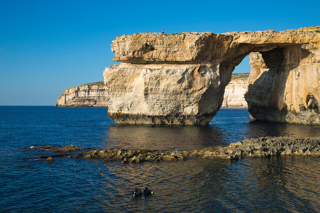 Divers in sea and Azure Window rock formation, near San Lawrenz, Gozo, Malta