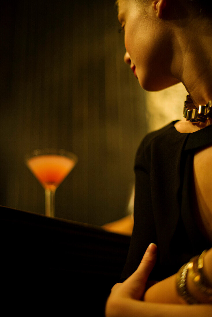 Woman sitting alone at bar with cocktail