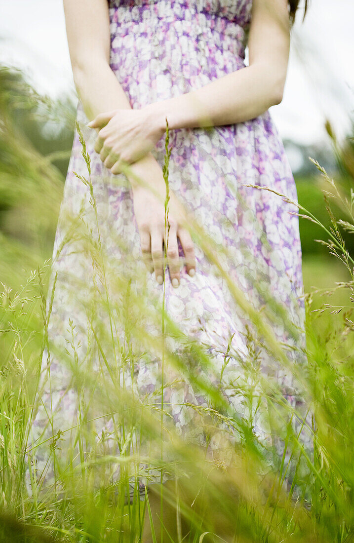 Woman standing in tall grass, cropped