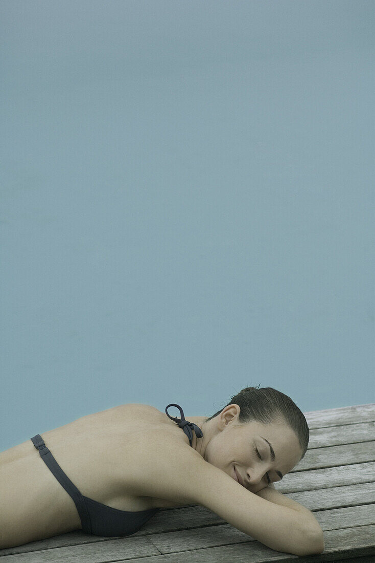 Young woman sunbathing in bikini beside pool