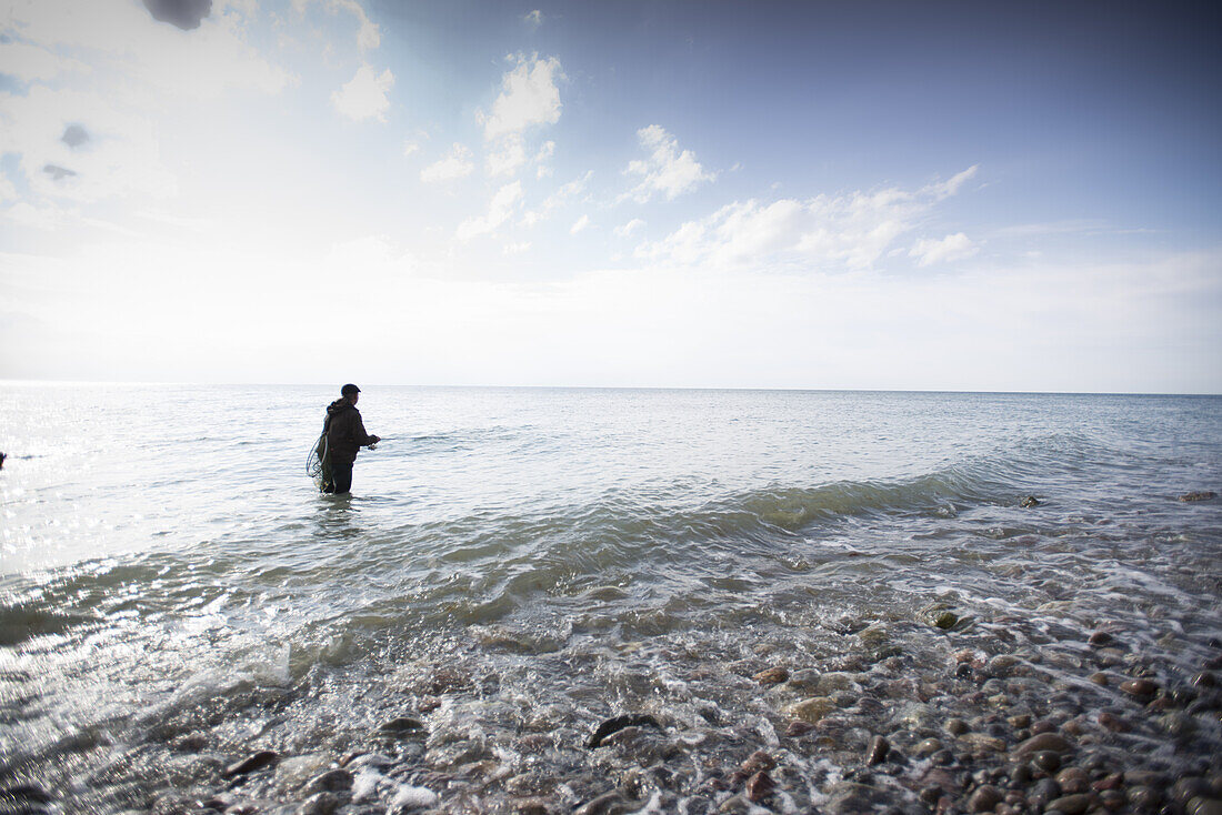 Fisherman is on the Baltic shore in the Hohen Western Pomerania Lagoon Area National Park, Ahrenshoop, Fischland-Darss-Zingst, Mecklenburg-Western Pomerania, Germany
