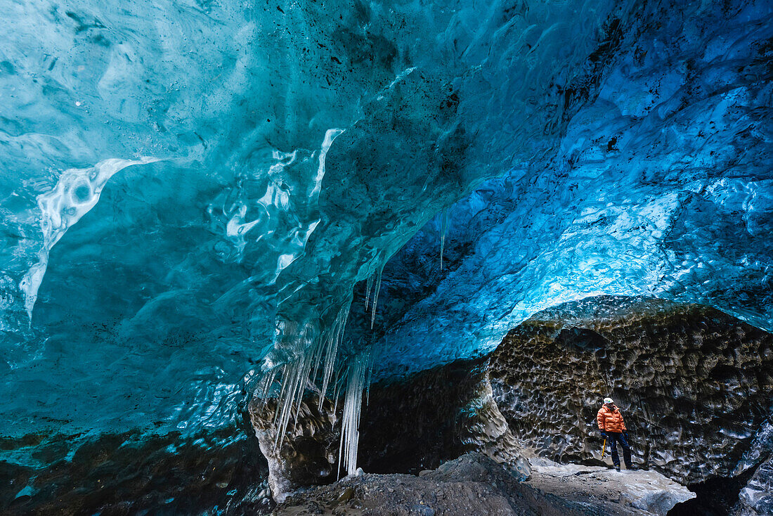 Mann mit Eispickel in blauer Eishöhle unter dem Vatnajökull-Gletscher,  Skaftafell Vatnajökull Nationalpark, Ostisland, Island, Europa