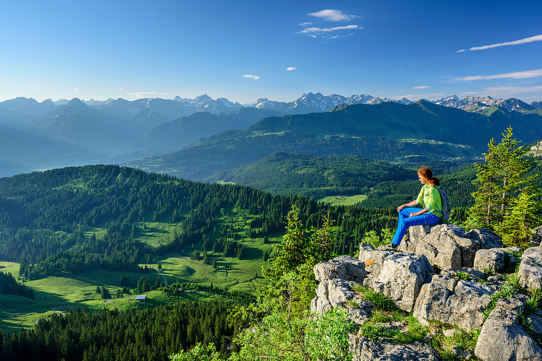 Woman hiking sitting on Besler and looking towards Allgaeu Alps, Besler, valley of Balderschwang, Allgaeu Alps, Allgaeu, Svabia, Bavaria, Germany