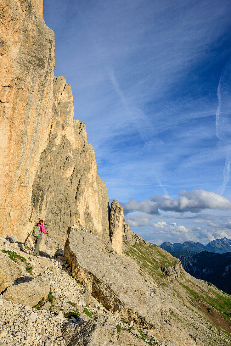 Frau beim Wandern geht unter Felswand hindurch, Rotwand, Rosengarten, UNESCO Weltnaturerbe Dolomiten, Dolomiten, Trentino, Italien