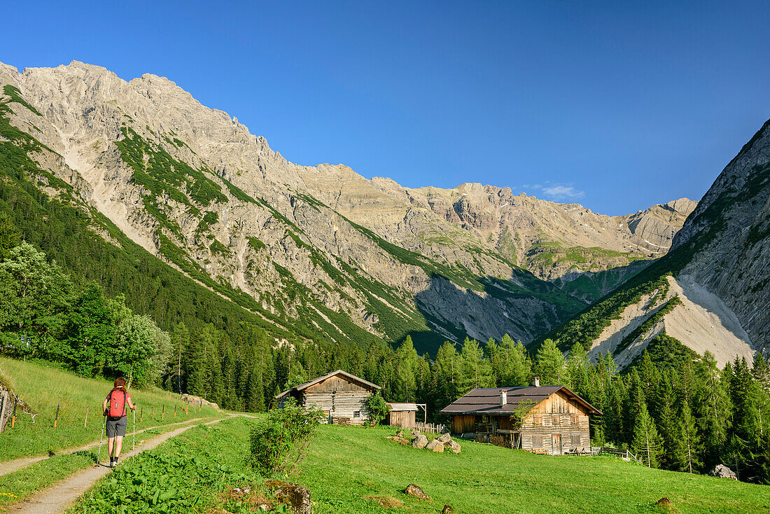 Frau wandert auf Weg an Almgebäuden vorbei, Fundaistal, Lechtaler Alpen, Tirol, Österreich