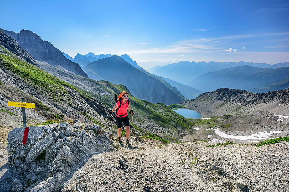 Woman hiking ascending towards Hinterseejoch, lake Vordersee in background, Lechtal Alps, Tyrol, Austria