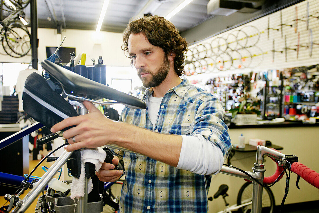 Caucasian man smiling in bicycle repair shop, Los Angeles, California, USA