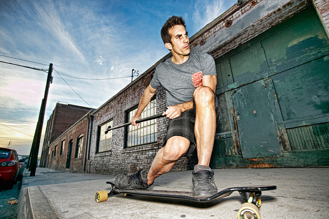 Caucasian man riding skateboard with land paddle, Los Angeles, California, USA