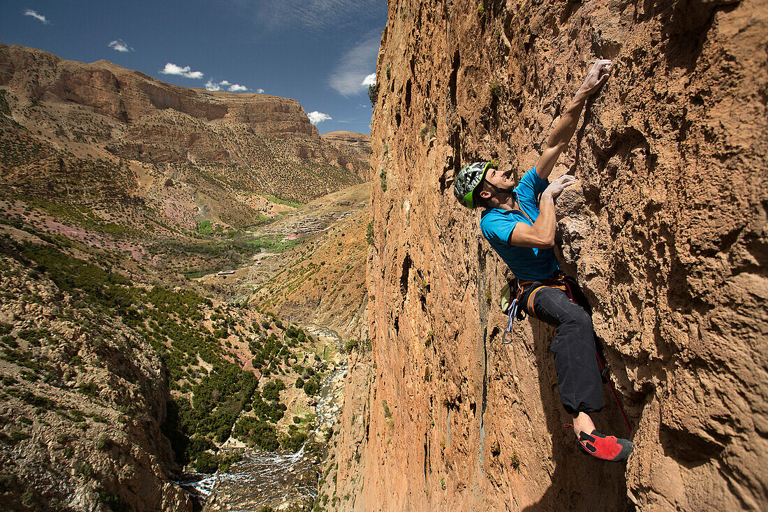 Climber scaling steep rocky cliff, Taghia, Tinghir, Morocco