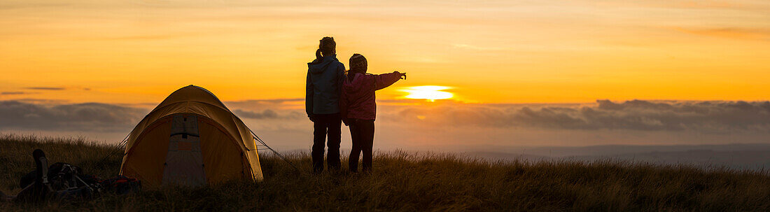 Silhouette of hikers overlooking remote landscape at sunset, Rural, None, UK