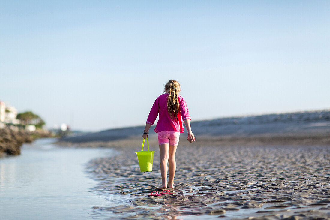 Caucasian girl carrying bucket on beach, Brunswick, Georgia, USA