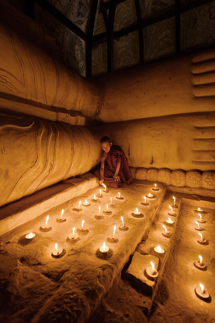Asian monk lighting candles in temple, Bagan, Mandalay, Myanmar