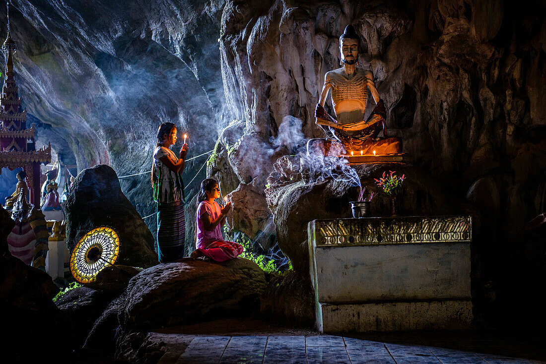 Asian girls lighting incense in temple, Hpa-An, Kayin, Myanmar