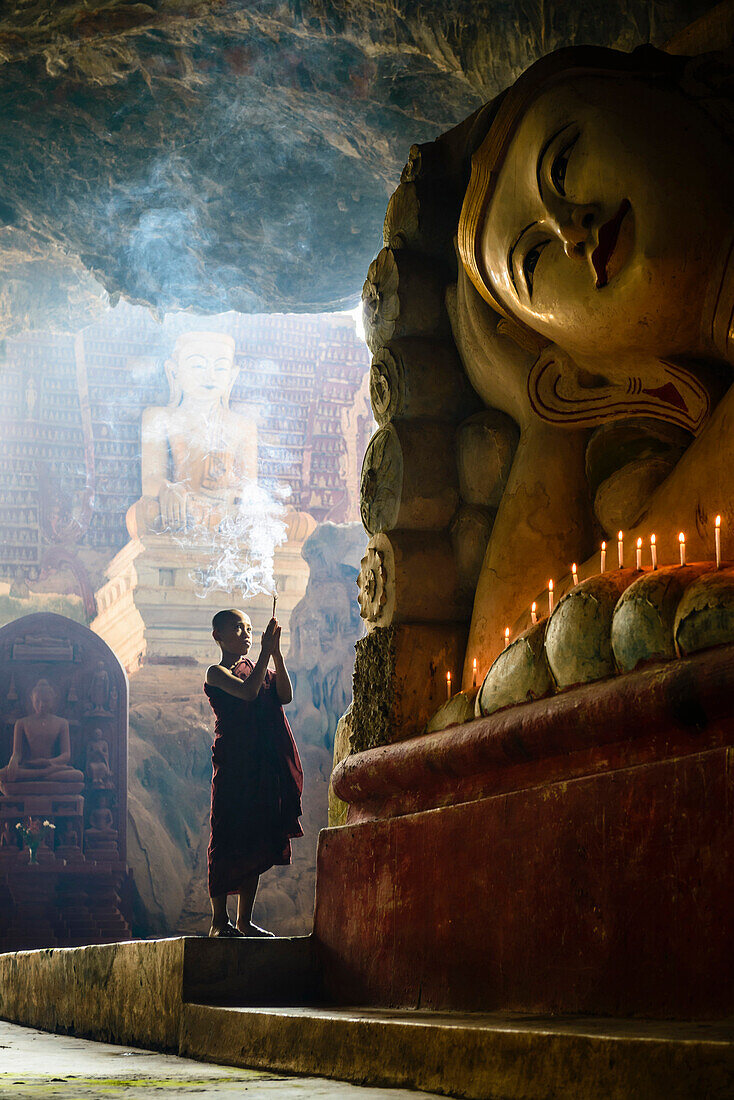 Asian monk lighting incense in temple, Hpa-An, Kayin, Myanmar