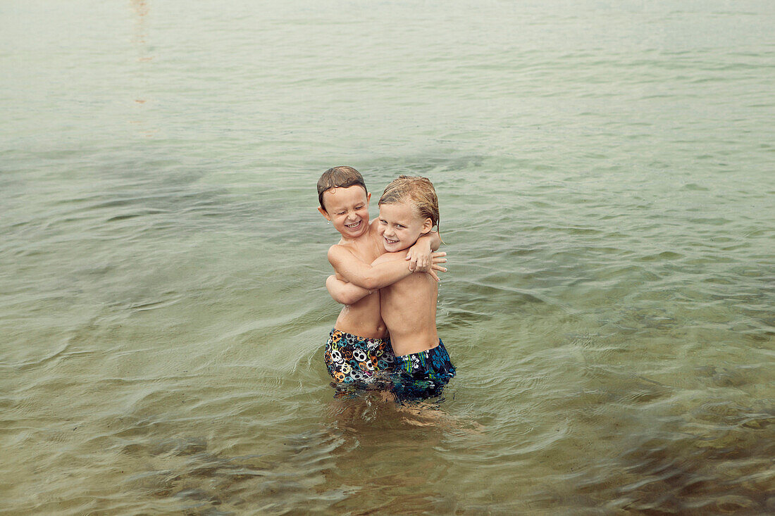 Caucasian boys hugging in lake, C1