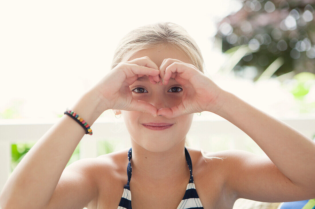 Caucasian girl making heart shape around eyes, C1