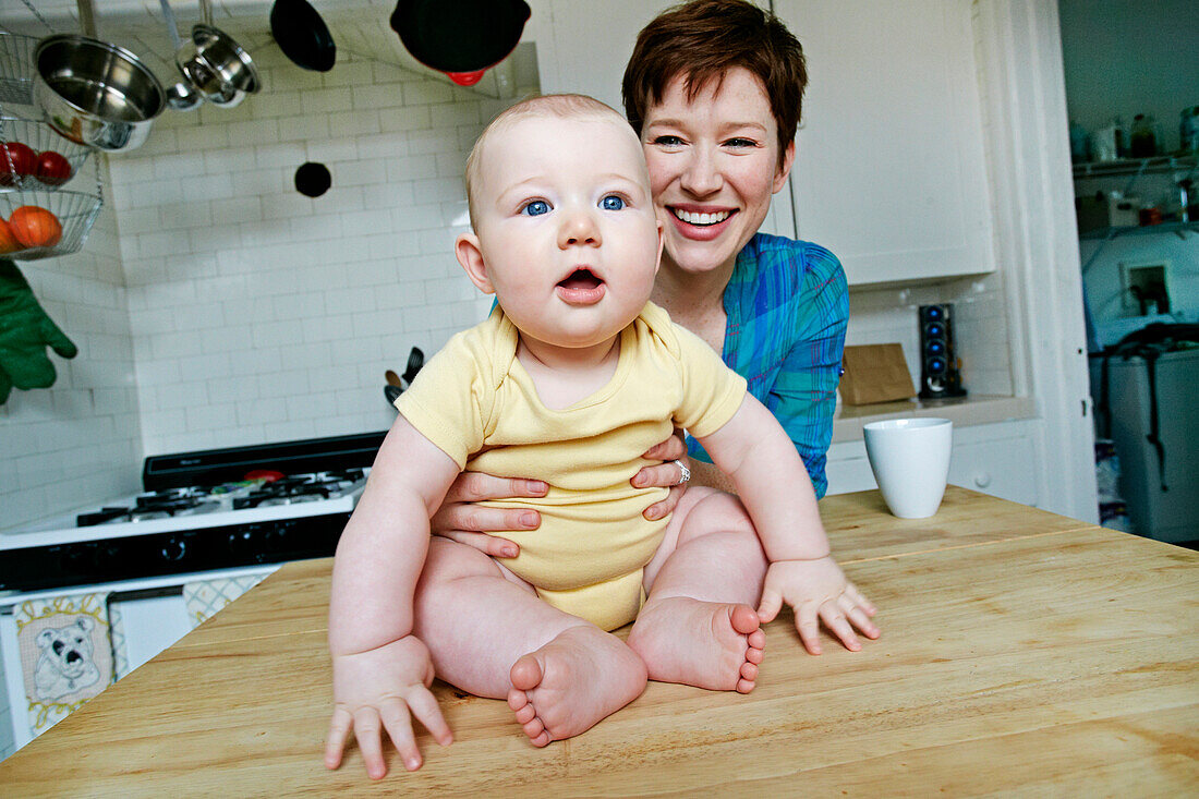 Caucasian mother and baby relaxing in kitchen, C1