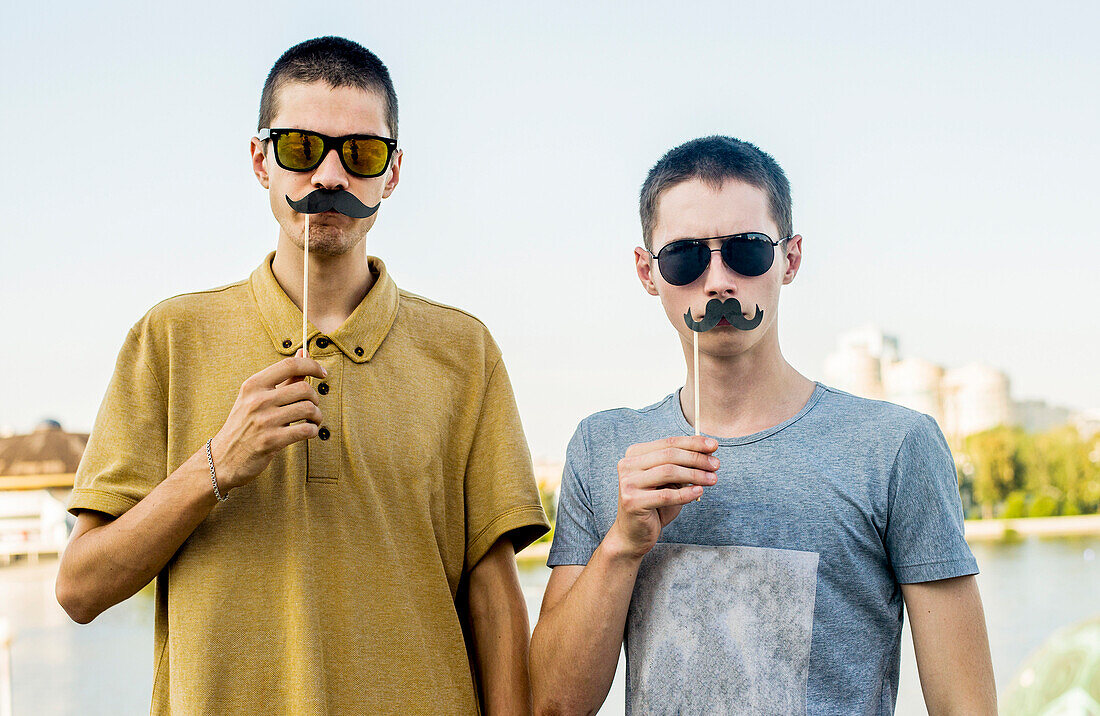 Caucasian men playing with fake mustaches in city, Yekaterinburg, Ural, Russia