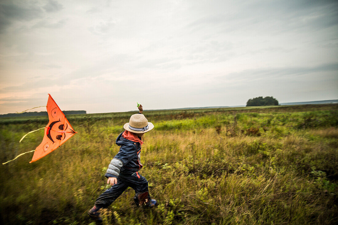 Caucasian boy flying kite in rural field, Ekaterinburg, Ural, Russia