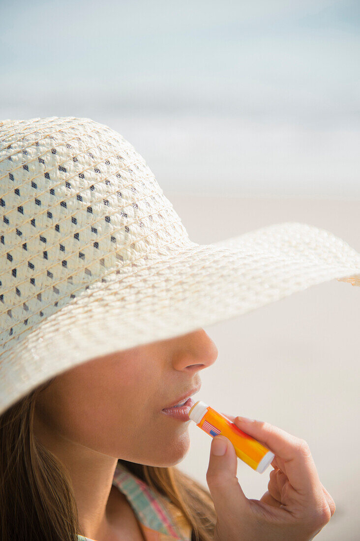 Caucasian woman applying sunscreen lip balm at beach, Jupiter, Florida, USA