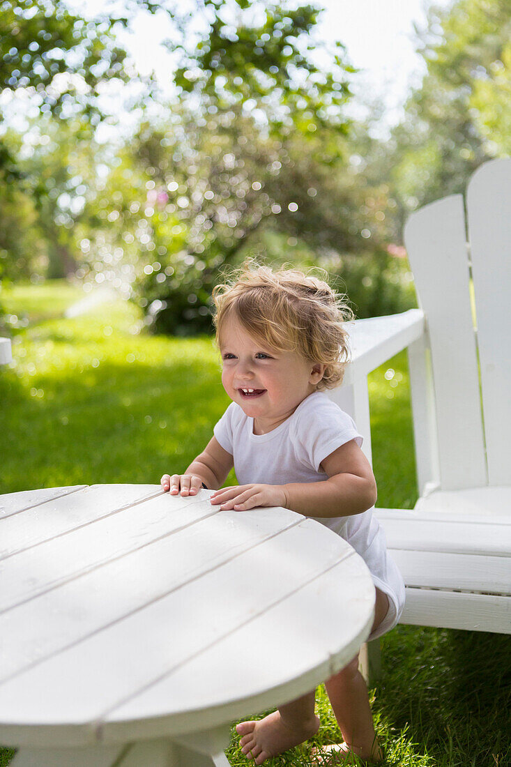 Caucasian baby boy standing at table in backyard, Hesperus, Colorado, USA