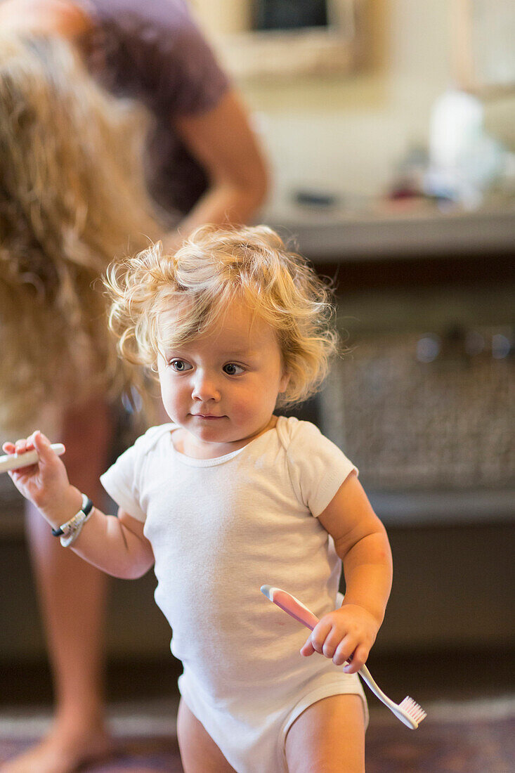 Caucasian baby boy holding toothbrush in bathroom, Santa Fe, New Mexico, USA