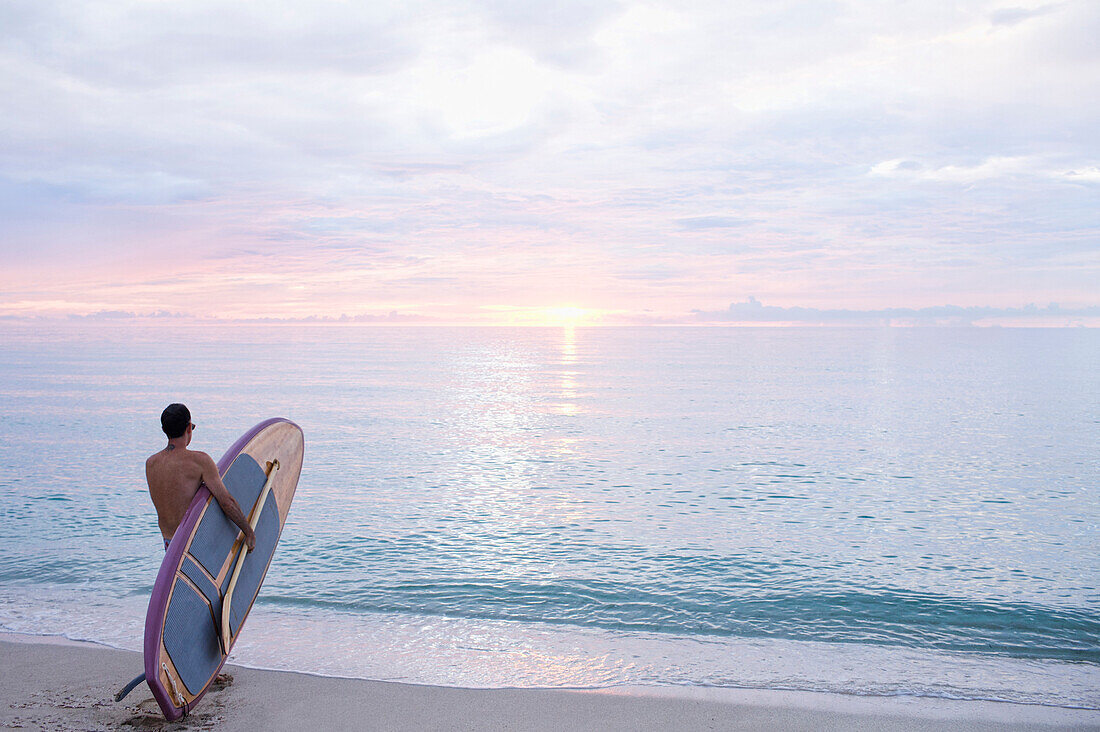Caucasian surfer holding paddleboard on beach, Miami Beach, Florida, United States