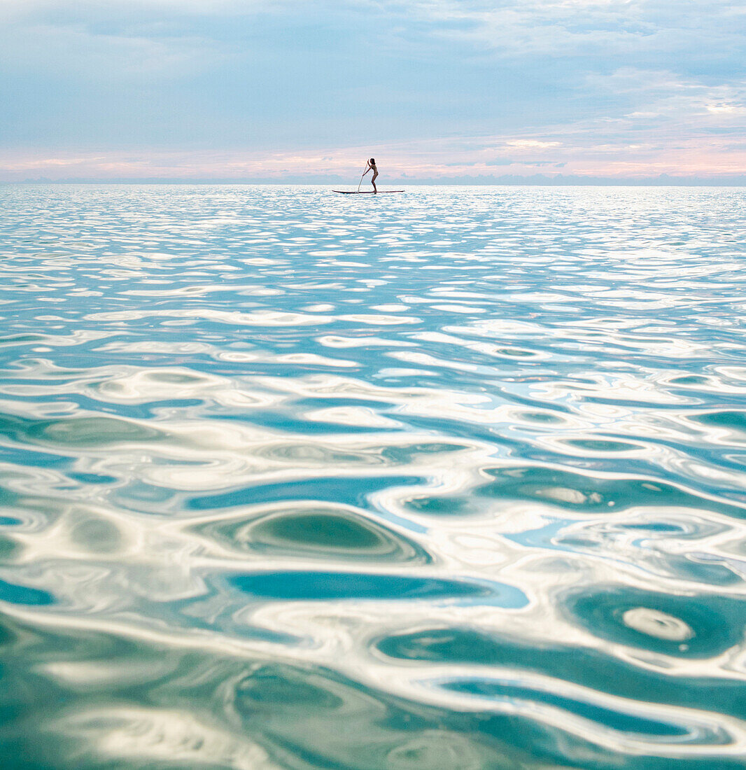 Mixed race woman standing on paddleboard in ocean, Miami Beach, Florida, United States